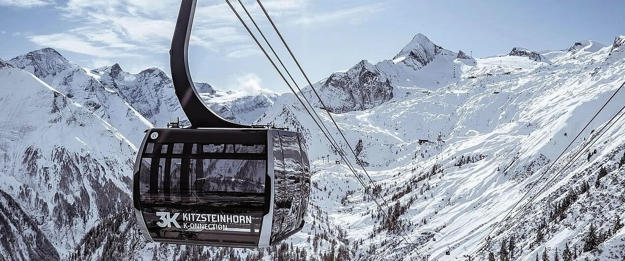 K-onnection | 260 m Nahaufnahme der 3K K-ONNECTION Gondel mit Aussicht auf die verschneiten Berge des Kitzsteinhorns, beliebtes Skigebiet in Österreich